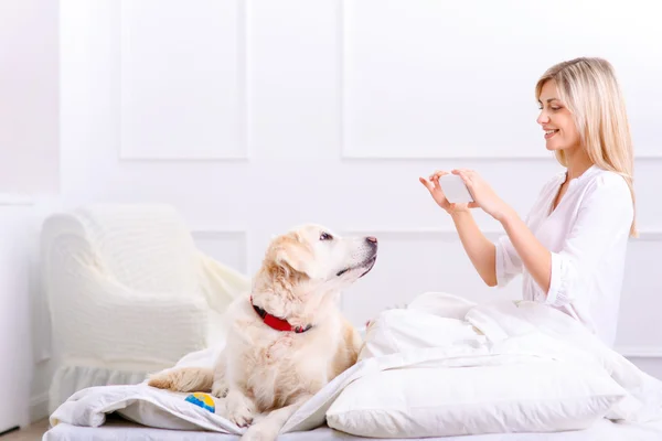 Mulher carinhosa deitada na cama com seu cão — Fotografia de Stock