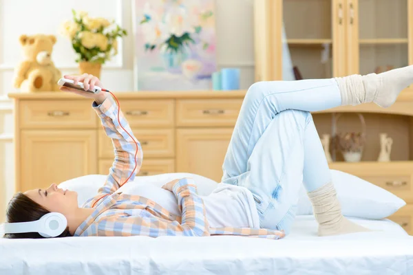 Adolescente deitada na cama e ouvindo música . — Fotografia de Stock