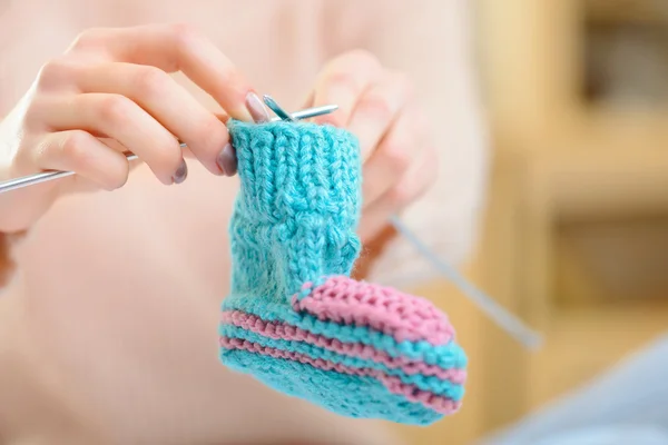 Giovane ragazza sta lavorando a maglia un calzino bambino . — Foto Stock