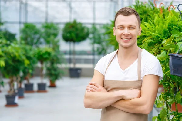 Jonge vrolijke bloemist binnen de serre. — Stockfoto