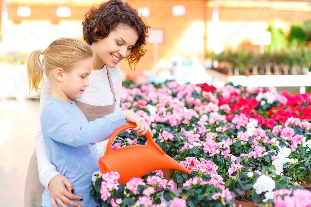 Little girl and florist watering flowers.