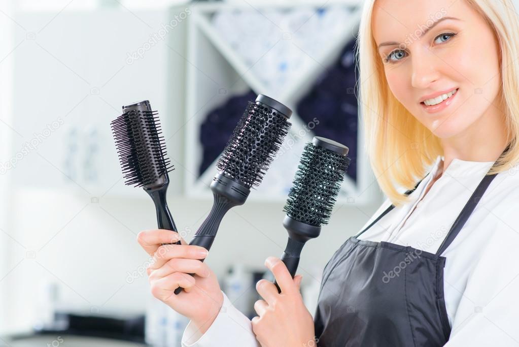 Hairdresser holding several hairbrushes.
