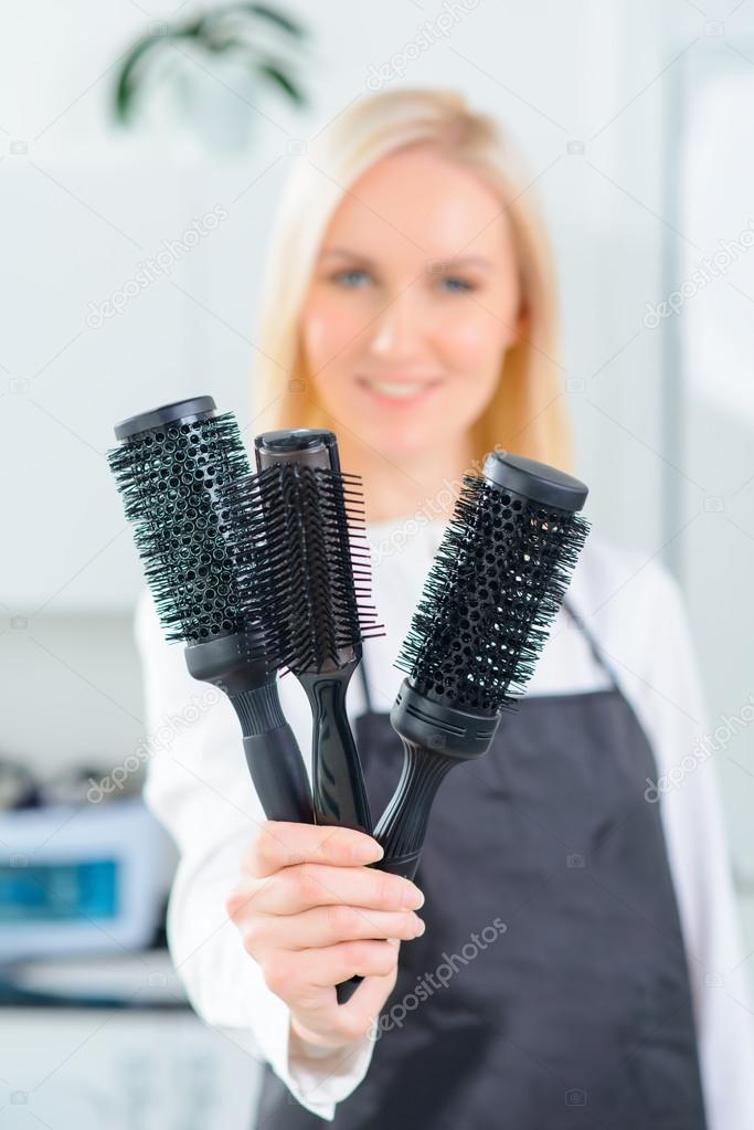 Hairdresser showing several hairbrushes.