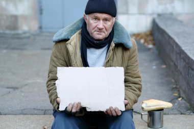Homeless man holding a cardboard sign. clipart