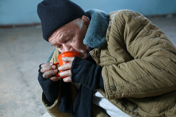 Homeless man hungrily drinking water.