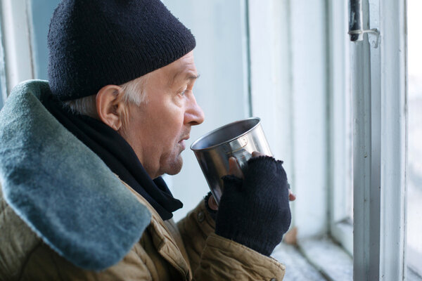 Homeless man holding his iron cup.