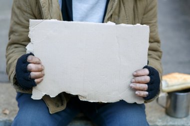 Evsiz adam elinde bir karton işareti.