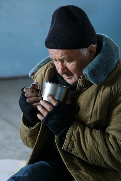 Homeless man holding his iron cup.