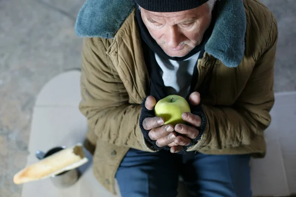 Ανώτερος άστεγους άνθρωπος που κρατά ένα μήλο. — Φωτογραφία Αρχείου