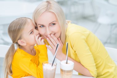 Happy mother and daughter sitting in the cafe