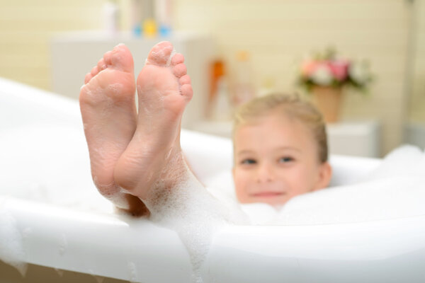 Pleasant little girl playing in bath tube