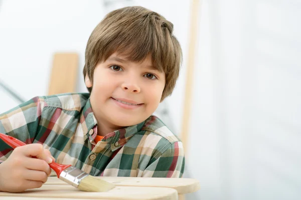 Chico sonriente pintando madera —  Fotos de Stock