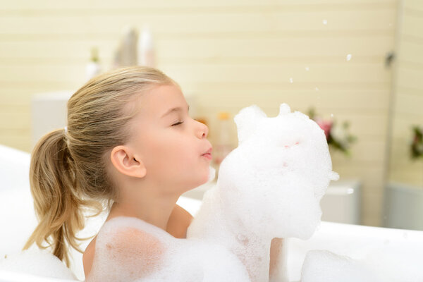 Pleasant little girl playing in bath tube