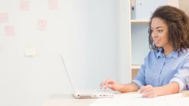 Young female employee is working on laptop.