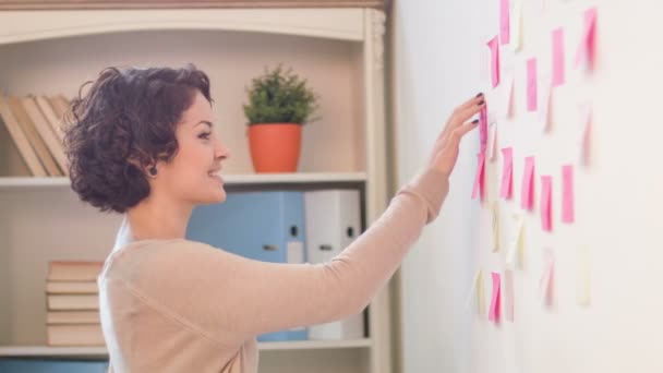 Medewerkers bevestigen post-it-noten aan de muur. — Stockvideo