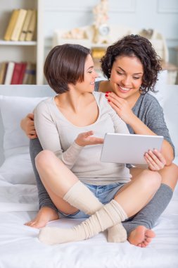İki kız kardeş bir şey bir tablet üzerinde tartışıyor.