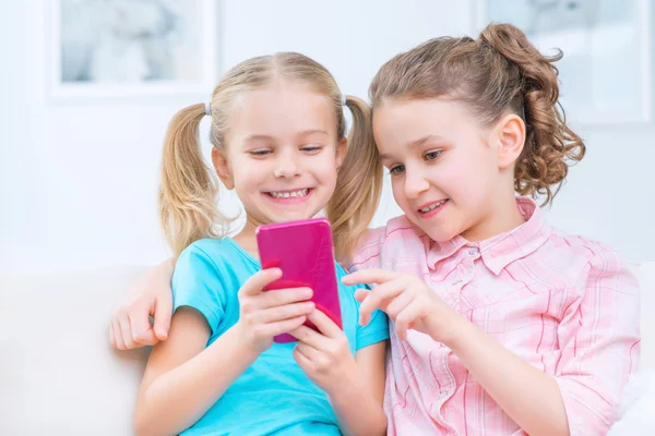 Cheerful little sisters sitting on the sofa — Φωτογραφία Αρχείου