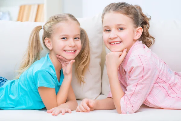 Cheerful little sisters sitting on the sofa — Stockfoto