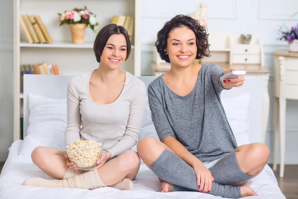 Zusters op bed zitten en kijken naar een film. — Stockfoto