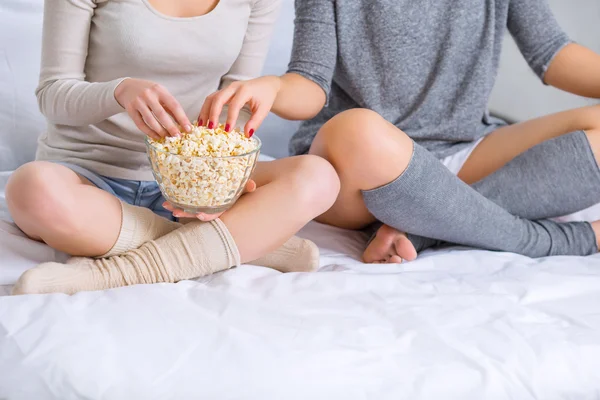 Systrar titta på film och äta popcorn. — Stockfoto