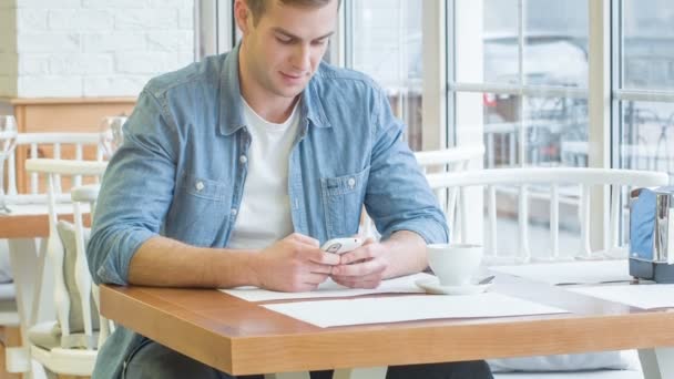 Joven hombre guapo está enviando mensajes en su teléfono inteligente . — Vídeos de Stock