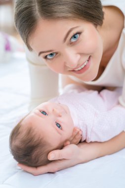 Küçük çocuğunu yatakta koyarak Hemşirelik Anne