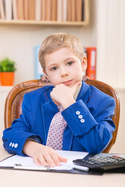 Little thoughtful boy sitting at the desk. — Stock Photo, Image