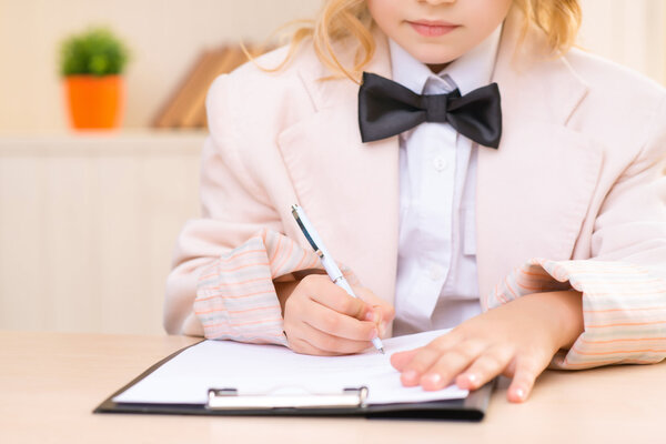 Little business girl is filling out a paper.