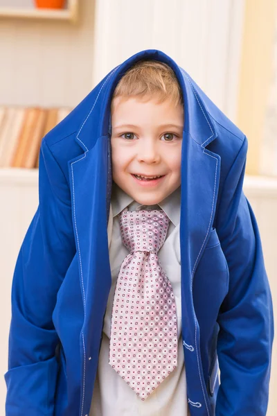 Lachende jongetje bedekt met volwassen jas. — Stockfoto