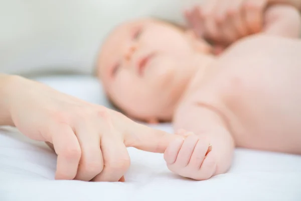 Младенец держит палец матери — стоковое фото