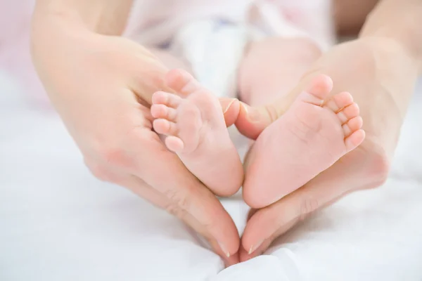 Nursing mother holding keeping legs of her infant — Stock Photo, Image