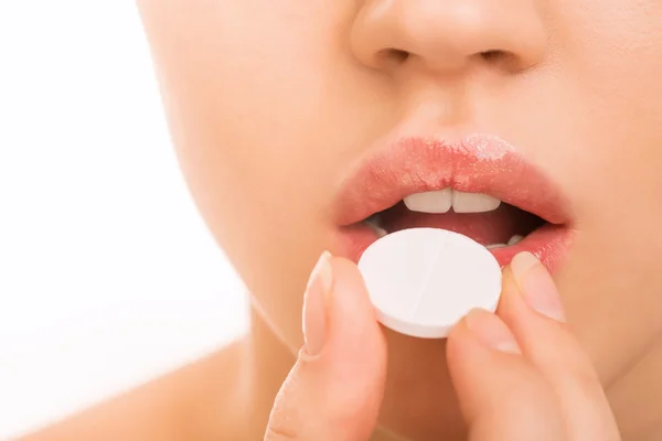 Young girl bringing a pill to her mouth. — Stock Photo, Image