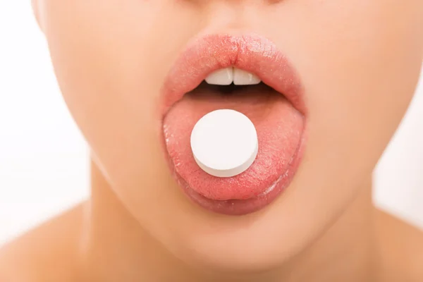 Jovencita manteniendo una píldora en su lengua . — Foto de Stock