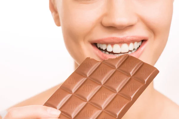Young smiling girl eating a chocolate bar. — Stock Photo, Image