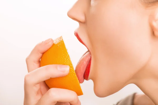 Młoda dziewczyna lizanie pomarańczowy. — Zdjęcie stockowe