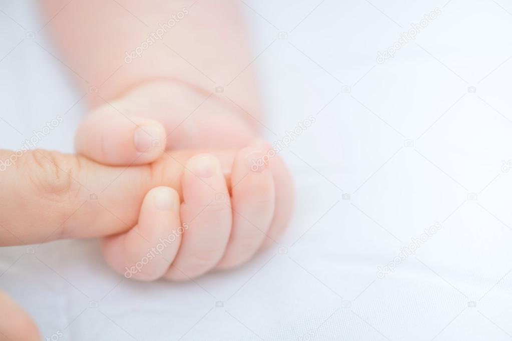 Infant holding finger of the mother