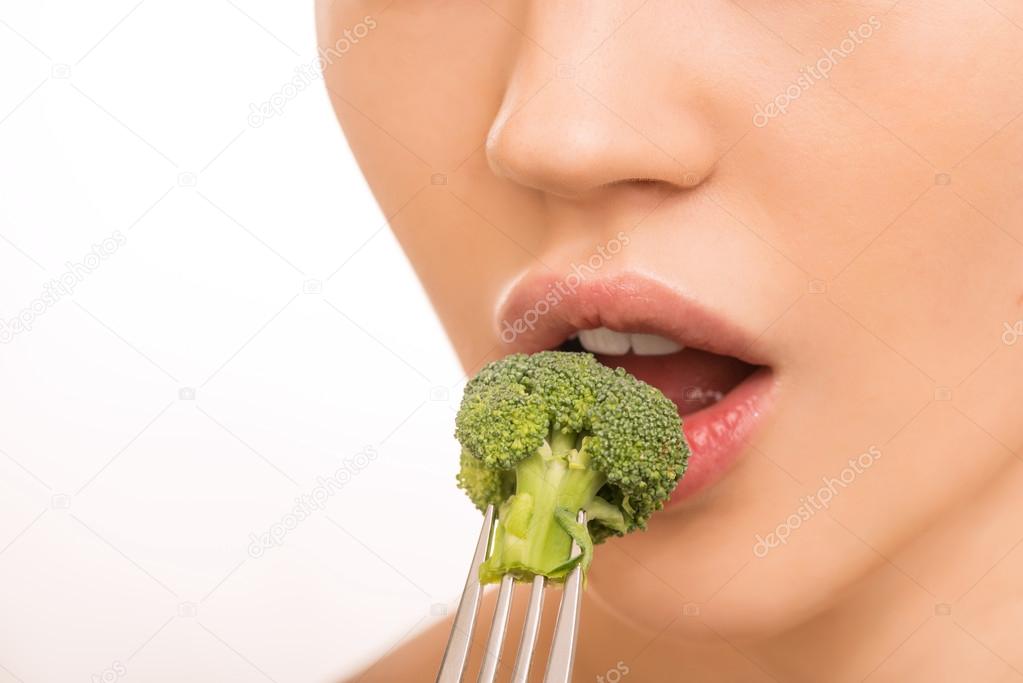 Young girl tasting a broccoli.