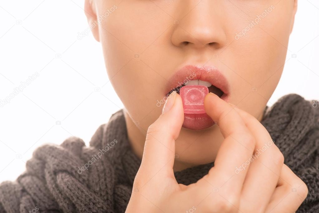 Young girl is taking a pill against sore throat.