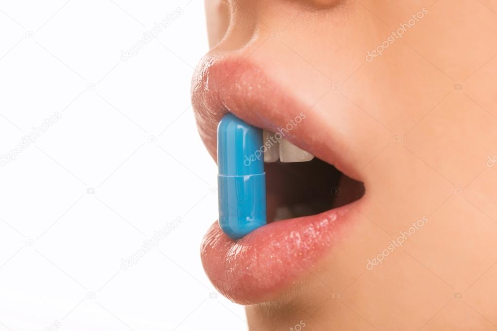 Young girl is holding a pill with her lips.