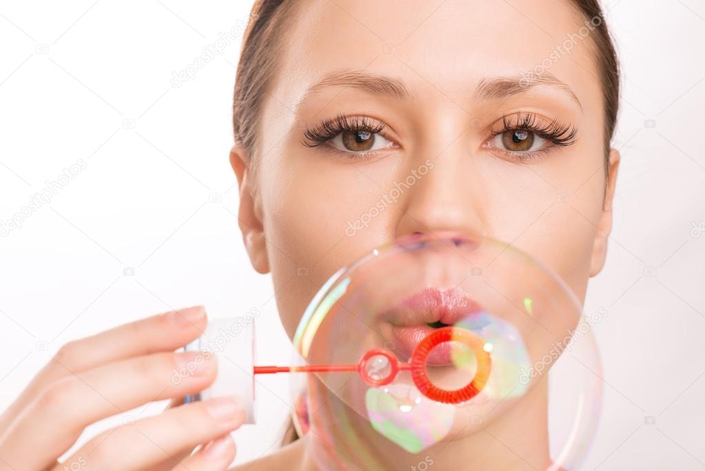 Young girl blowing out a soup bubble.