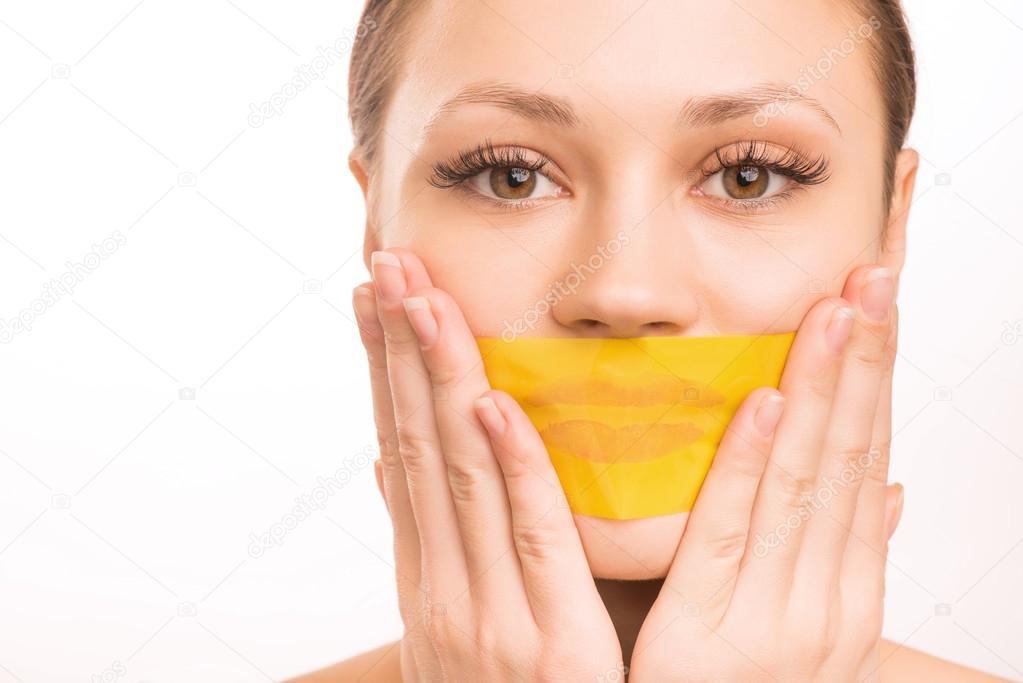 Young girl taping her mouth.