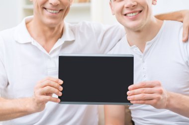 Father and adult son holding tablet