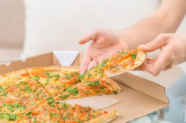 Hungry person holding piece of pizza
