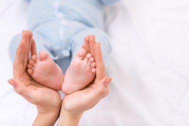Mother holding her baby boys feet. clipart