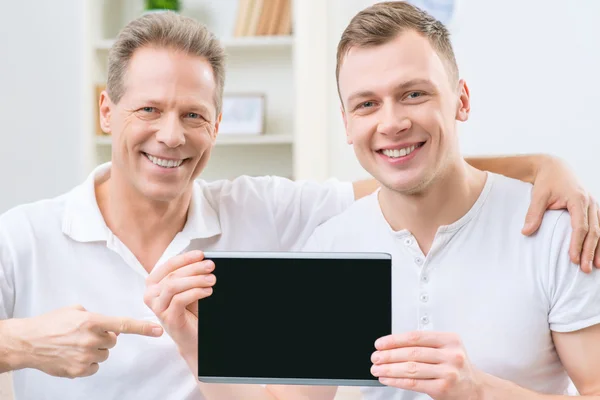 Pai e adulto filho segurando tablet — Fotografia de Stock