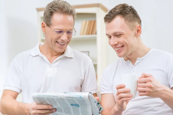 Father and adult son reading newspaper — Stockfoto