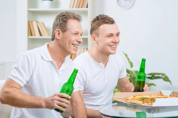 Pai e filho bebendo cerveja e comendo pizza — Fotografia de Stock