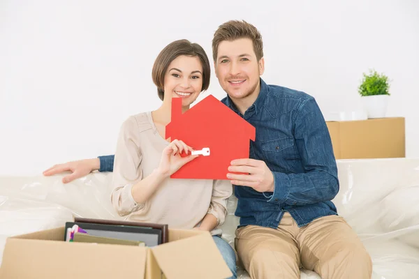 Couple holding little red house and key — Stockfoto