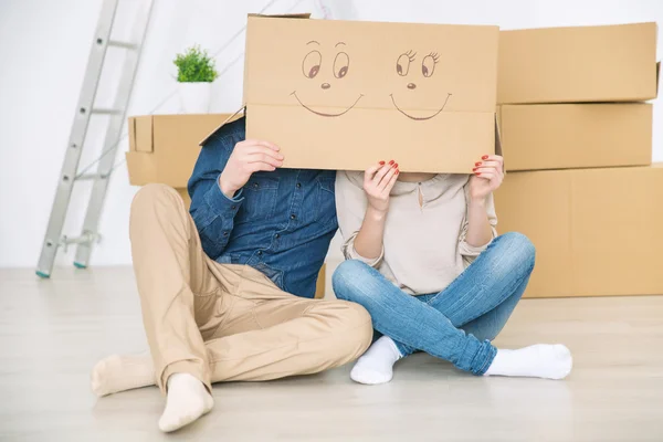 Casal alegre escondido sob a caixa — Fotografia de Stock