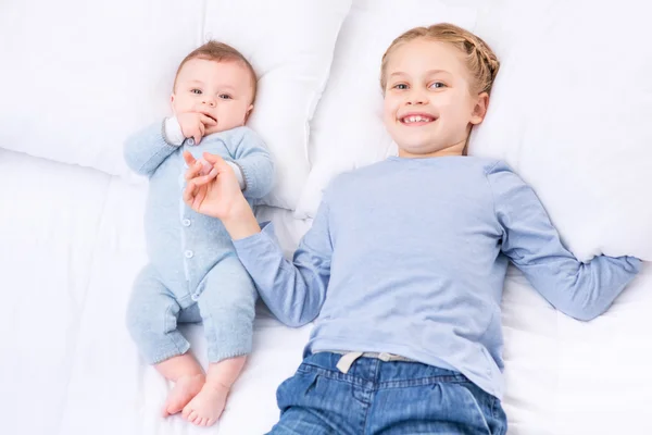 Hermana y hermanito acostados en la cama — Foto de Stock